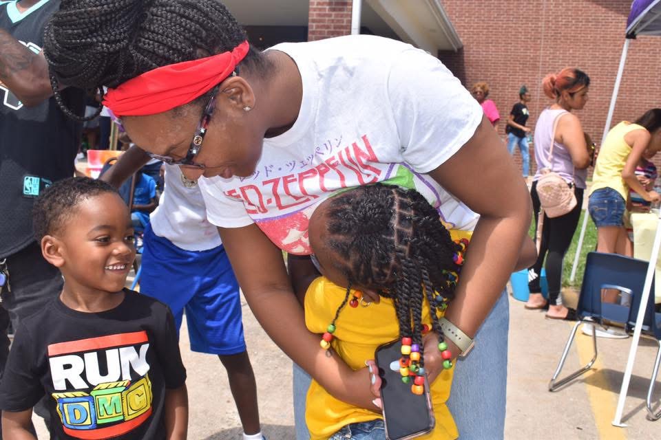 An adult shares a happy moment with two children at a community event.