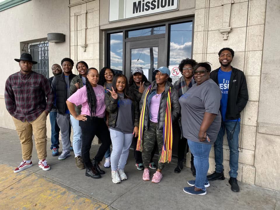 An outreach group gathers outside a Mission building.